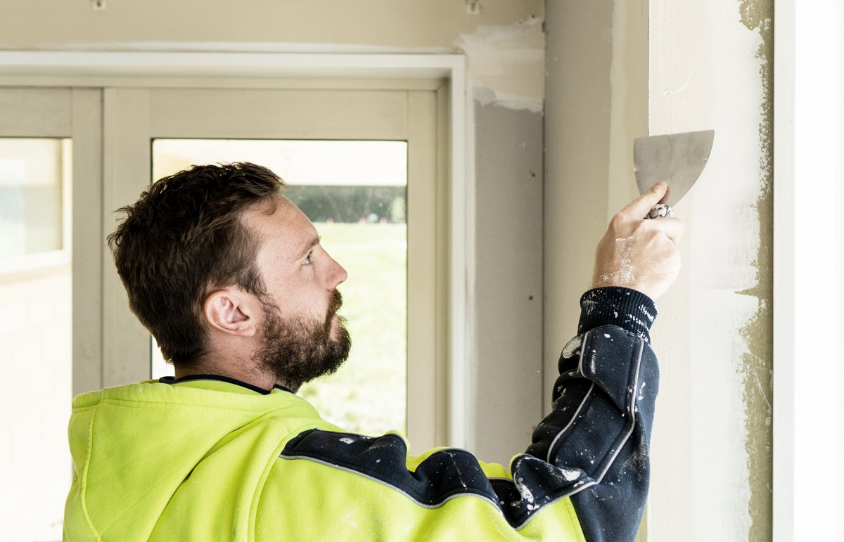 Man In High Visibility Wear Plastering An Internal Wall